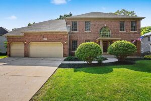 Front exterior of 205 Willowwood Drive Oswego IL — brick-front 4-bedroom home with 3-car garage and landscaped yard